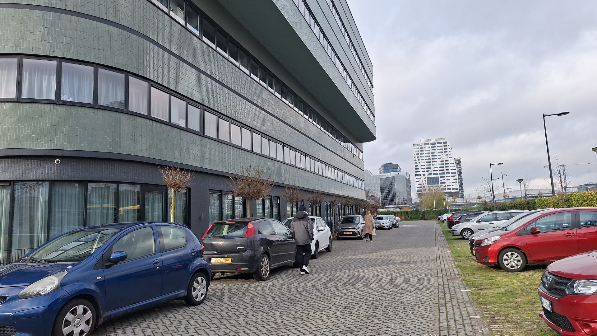 Parkeerplekken rondom het bestaande gebouw van de Jan van Foreeststraat. Op de achtergrond het Stadskantoor van de gemeente Utrecht.