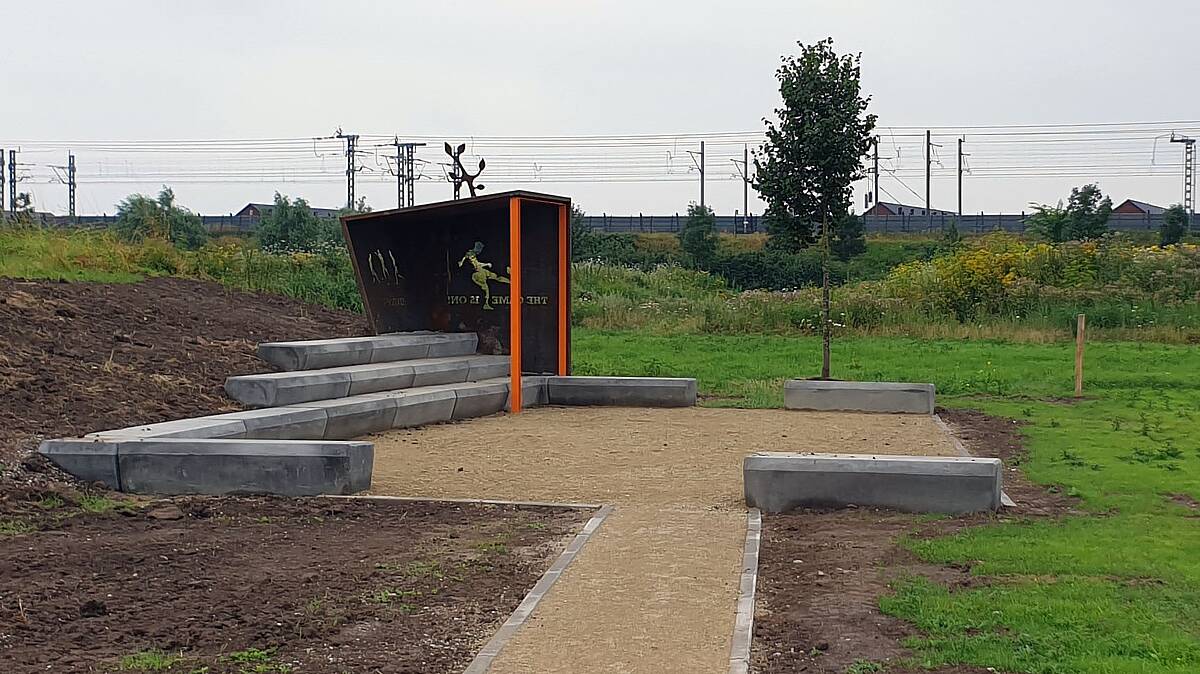 Voorbeeld jongeren plek met een overkapping, stenen (zit)trappen en een zand veldje eraan