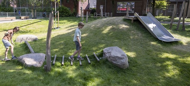 Natuurlijk spelen voorbeeld: keien en houten lattenbrug, houten palen, heuvel
